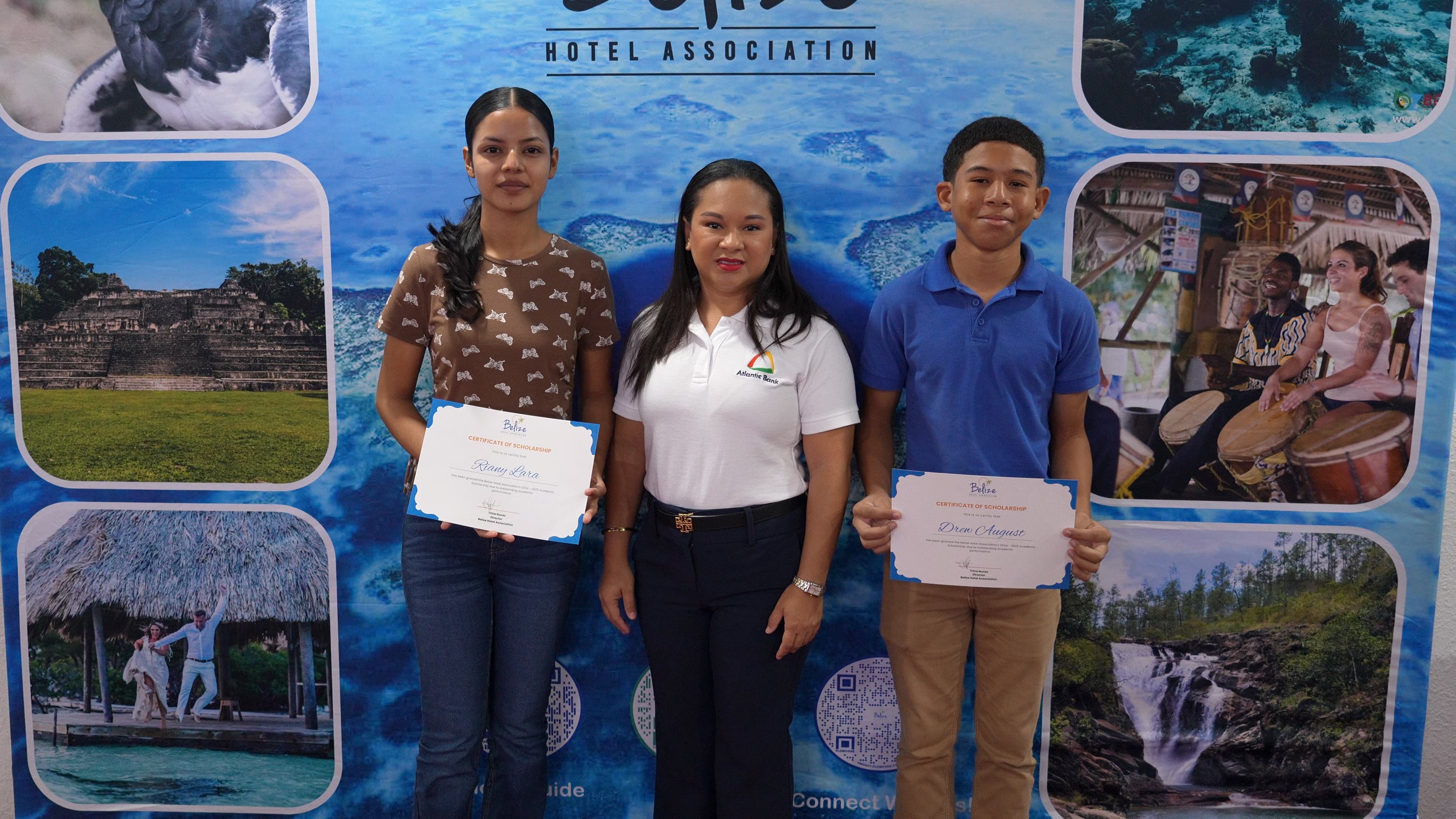 Three individuals stand in front of a vibrant backdrop, holding scholarship certificates from the Belize Hotel Association.