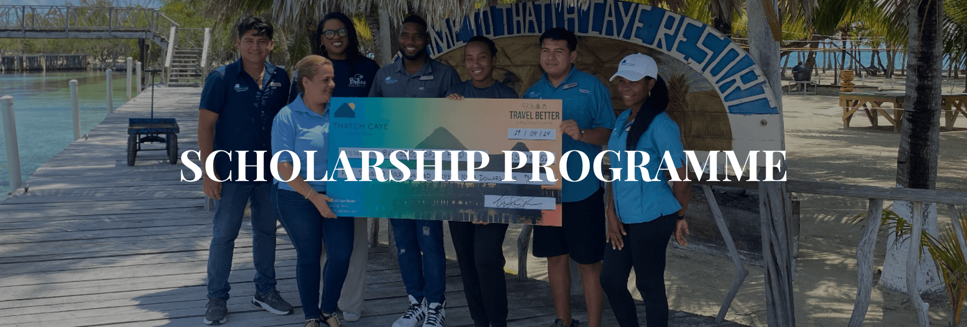 A group poses with a large scholarship check at Thatch Caye Resort.
