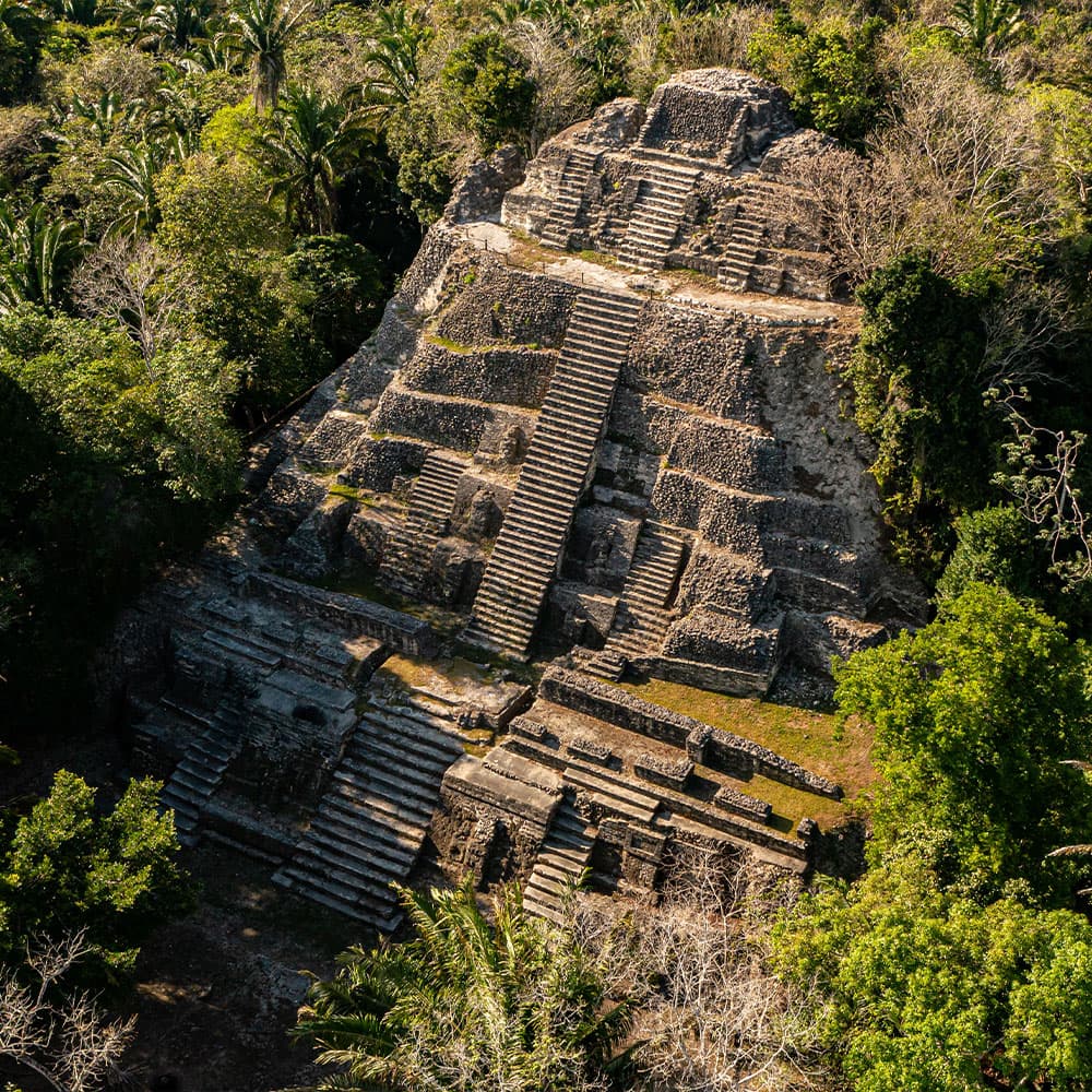 Aerial view of a stepped pyramid surrounded by lush greenery.
